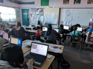 Students in a classroom using Scratch on their laptops
