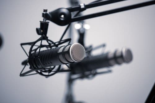 podcasting- two microphones hanging from a pole facing the camera