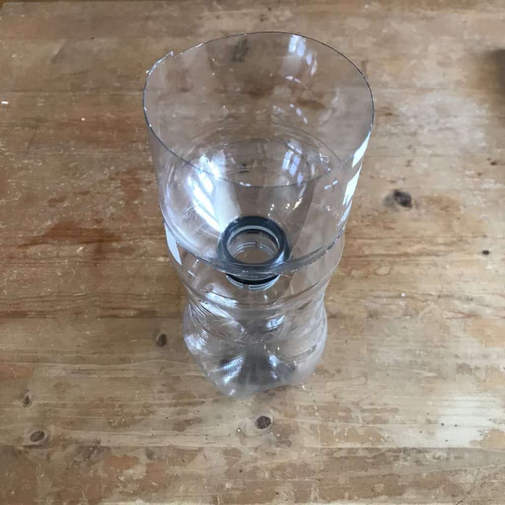 The water bottle cut in half with the top half upside down in the bottom half.