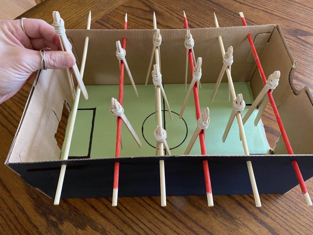 Placking popsicle sticks tied together with a rubber band on top of red and white rods.