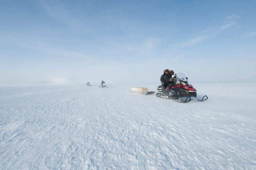 snowmobile is sitting close to the right hand side, and there is snow.