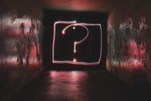 A question mark surrounded by a neon pink box with light illuminating the sides.