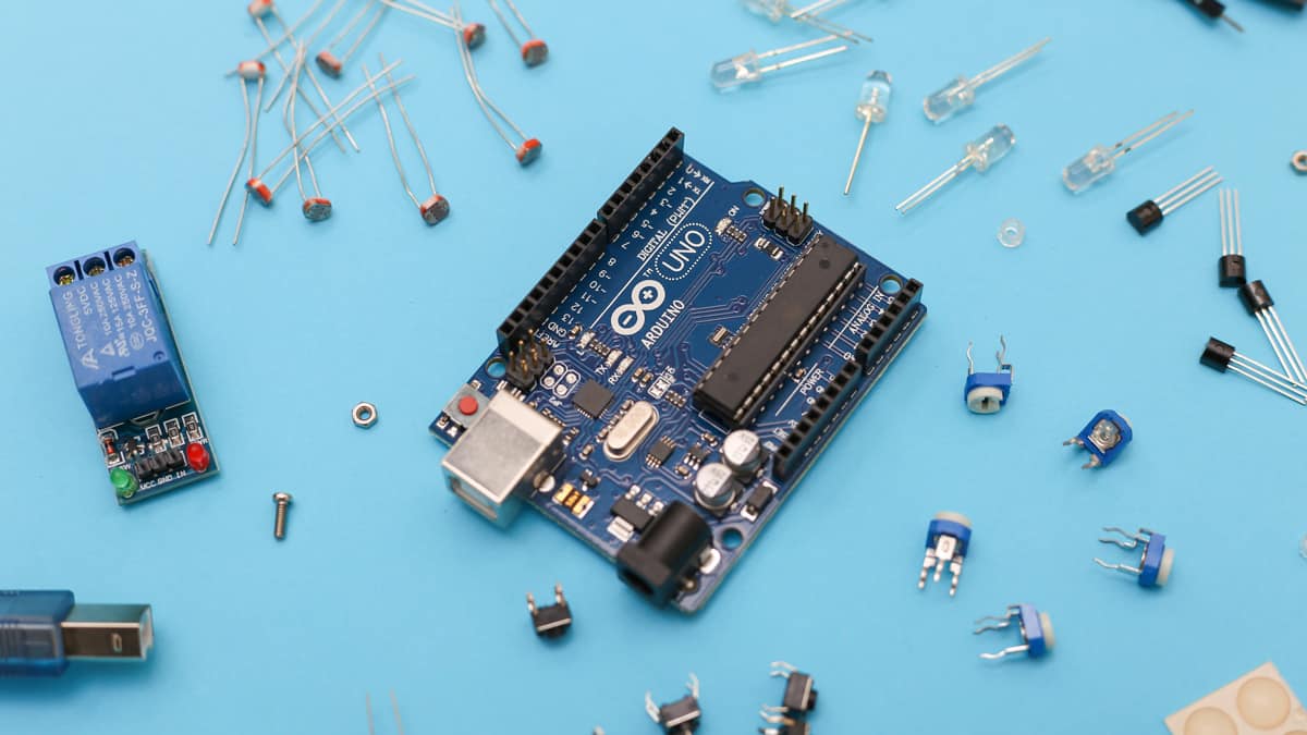 Arduino Uno and electronic parts on a blue surface.
