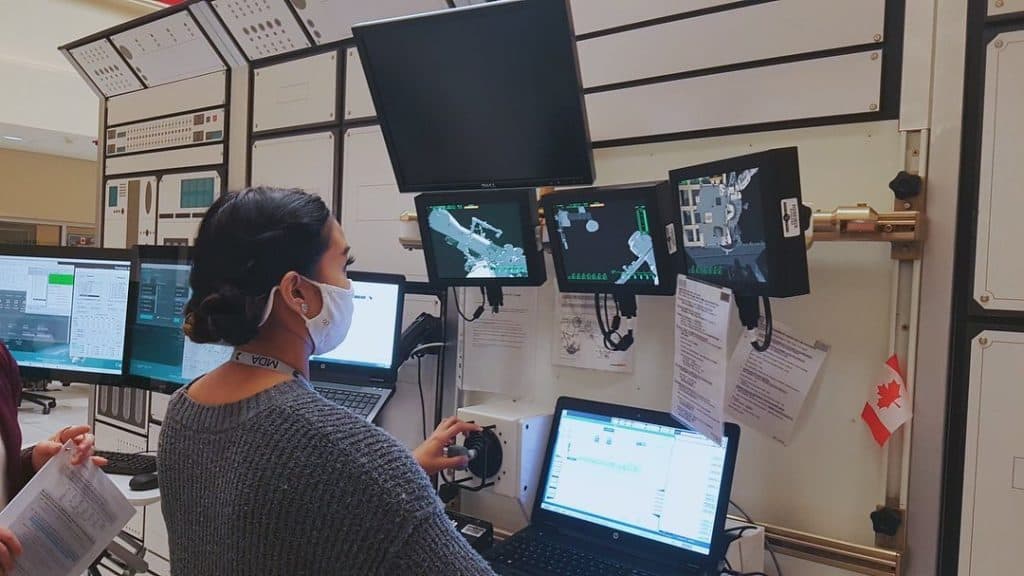 Abby Lacson participating in a simulation, maneuvering the Canadarm 2 around the ISS through an assortment of screens