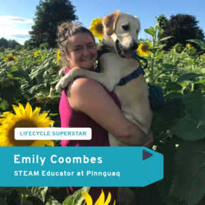 Emily Coombes standing in a sunflower field and holding a golden retriever.