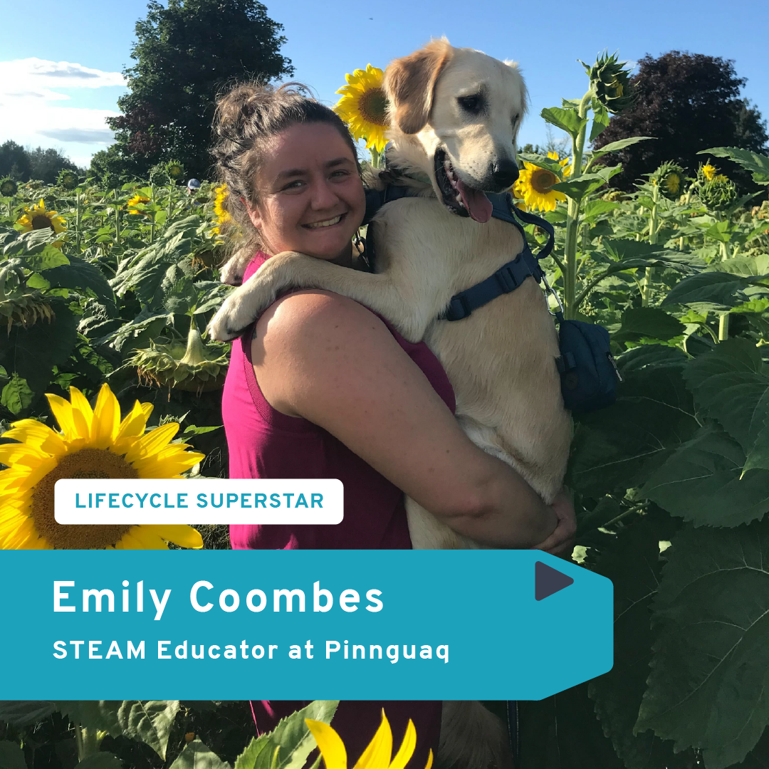 A photo of a EMily Coombes, standing in a sunflower field and holding a golden retriever.