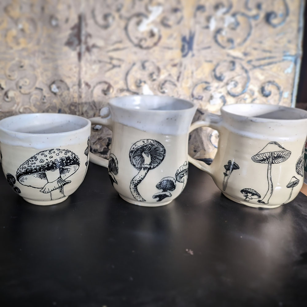 A set of three mugs with black mushroom designs.