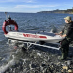 Someone who looks to be launching a boat into a body of water.